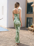 Back view of a woman in a green floral print maxi dress with tie straps.