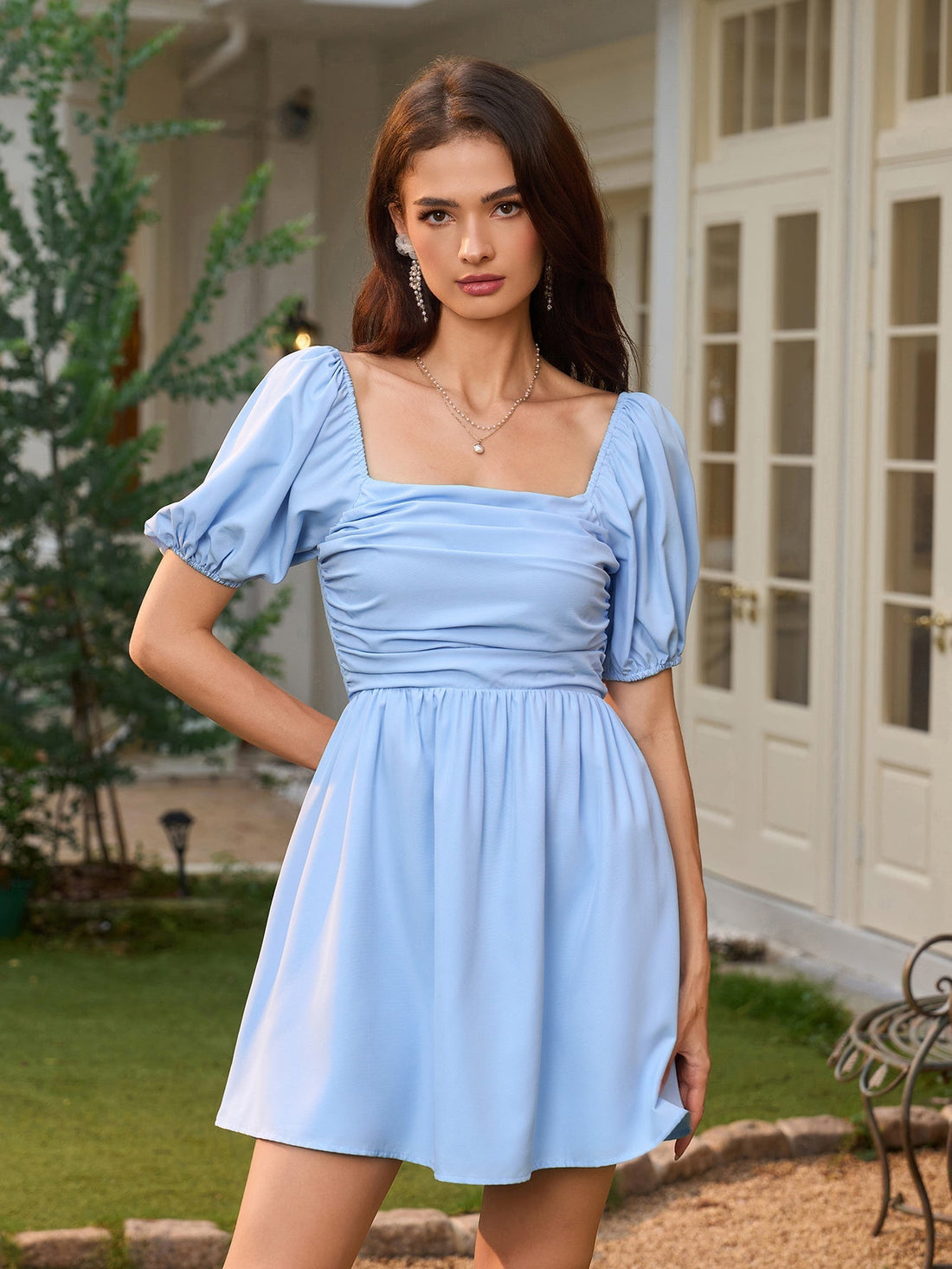 Woman in a light blue short puff sleeve square neck dress standing outdoors