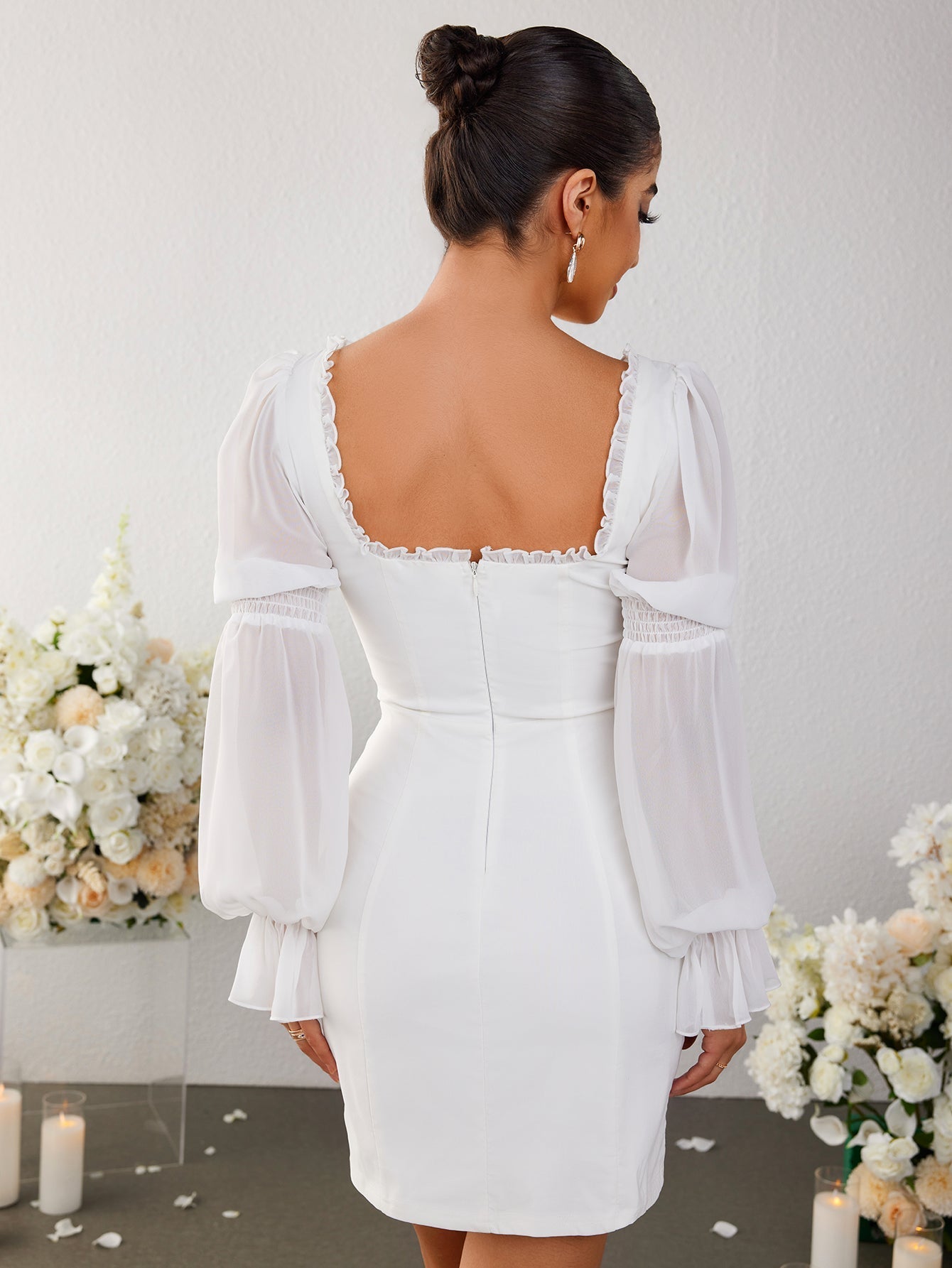 Back view of a white sheath dress with sheer bishop sleeves.