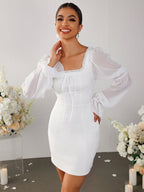 Woman posing in a white sheath dress with sheer bishop sleeves.