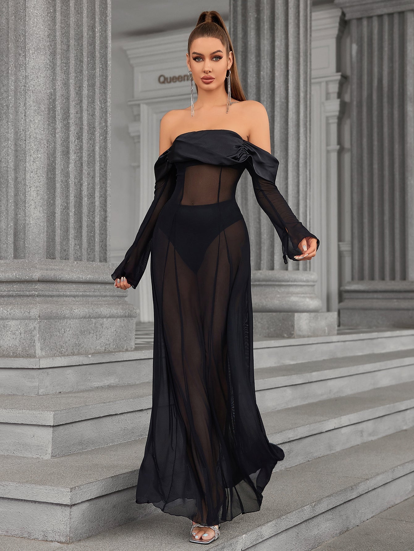 Woman walking in a black off-the-shoulder sheer mesh maxi dress.