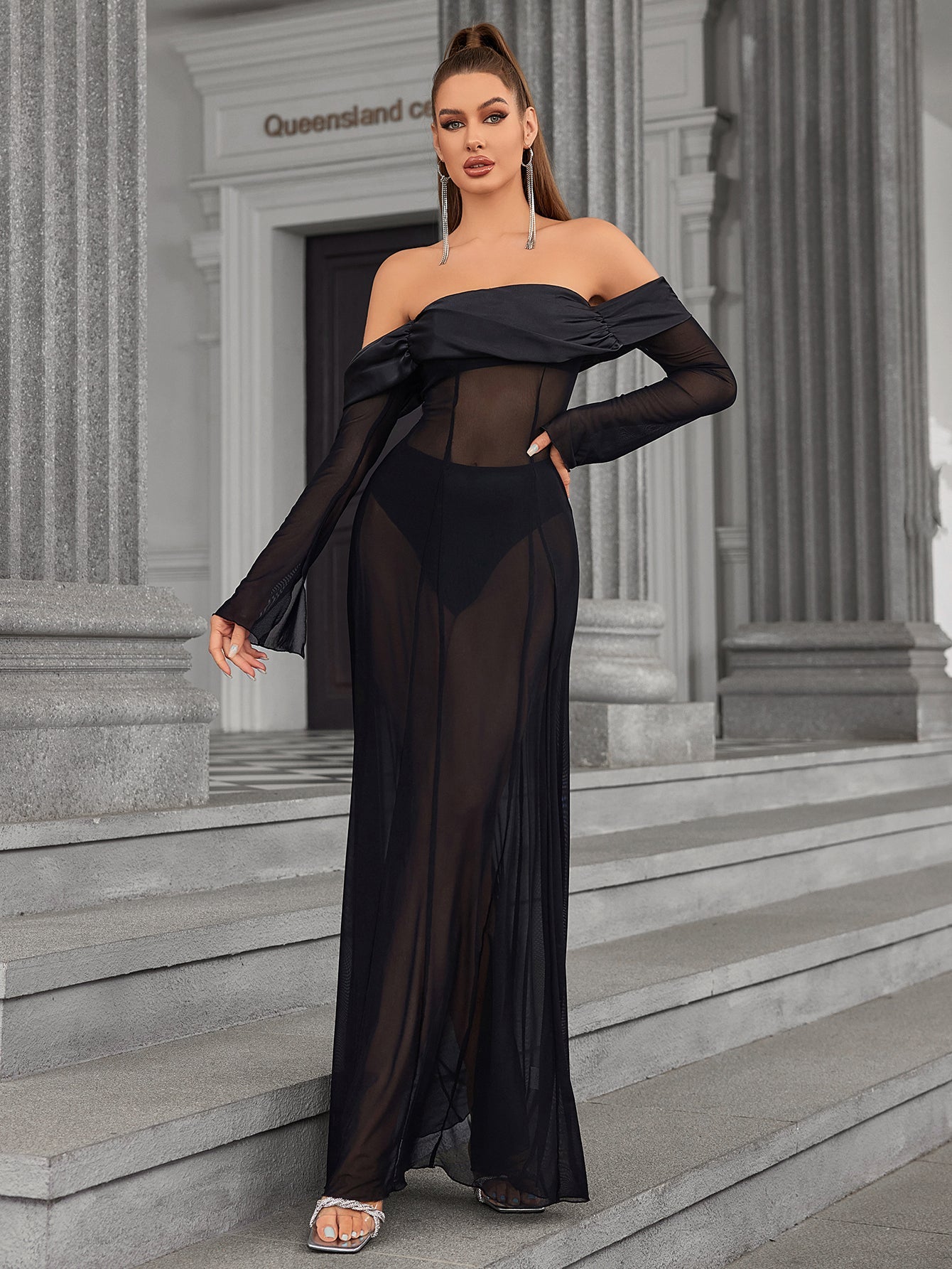 Woman posing in a black off-the-shoulder sheer mesh maxi dress.