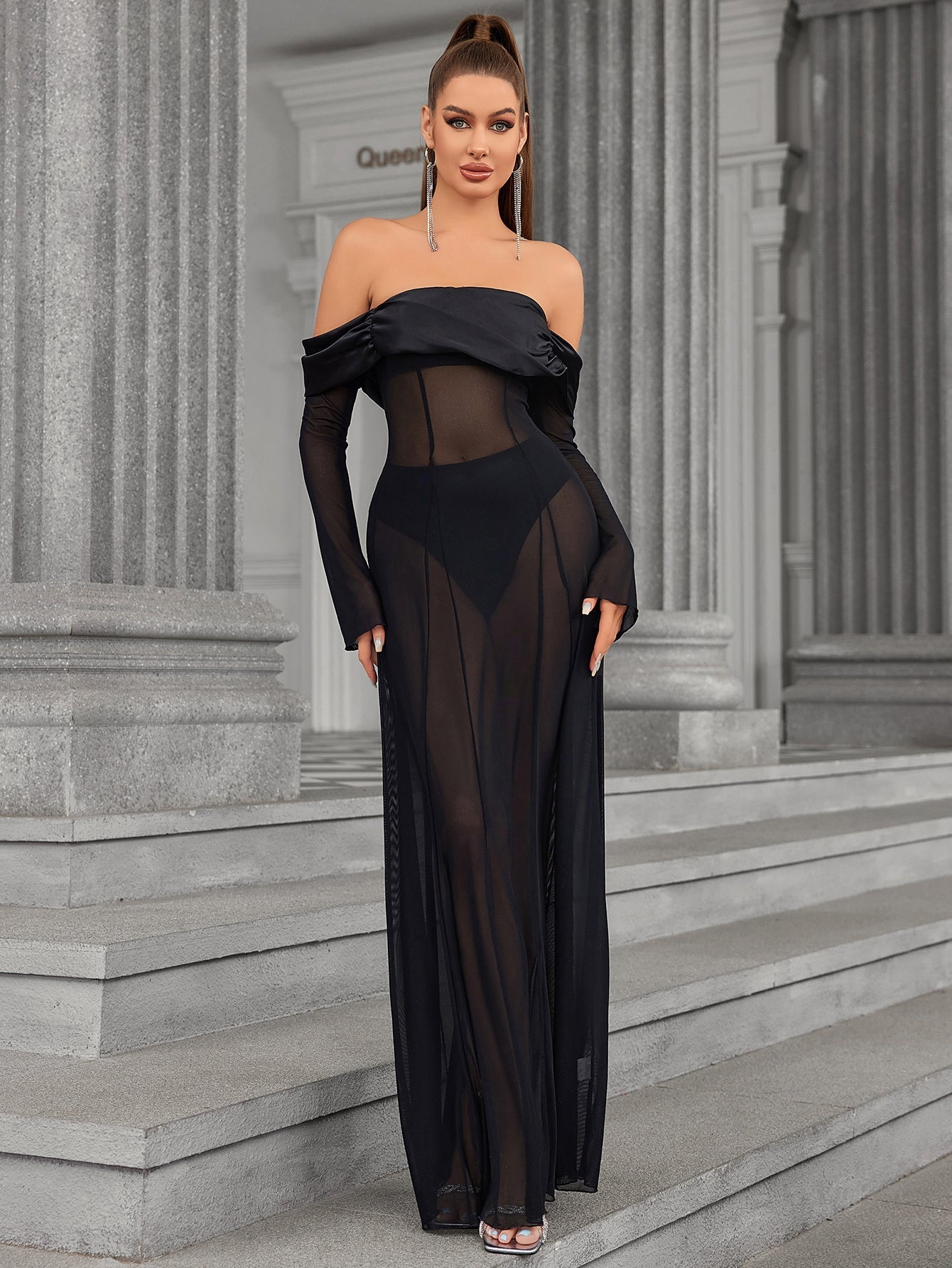 Full-length front view of a woman in a black sheer mesh maxi dress.