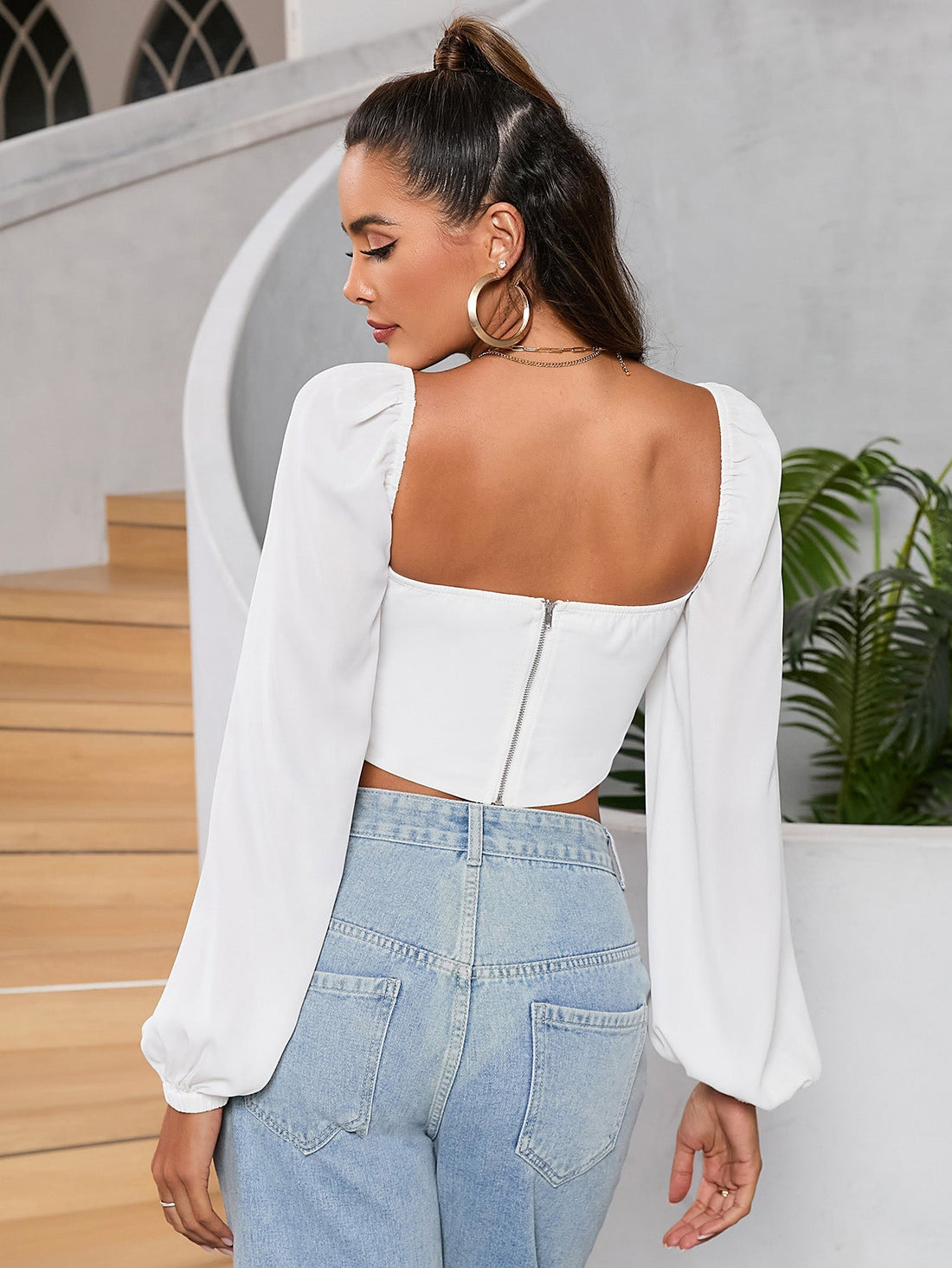 Woman wearing a white long sleeve cropped top with a sweetheart neckline and drawstring detail.