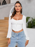 Model wearing a white cropped top with puff sleeves and a sweetheart neckline.