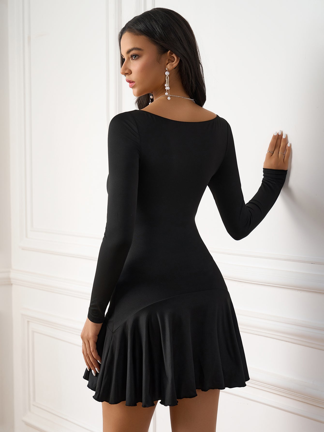 Back view of a woman in a black long-sleeved dress with a flared hem.