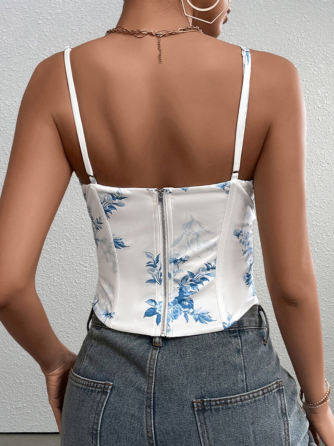 Back view of a woman in a white floral print corset top with a zipper closure.
