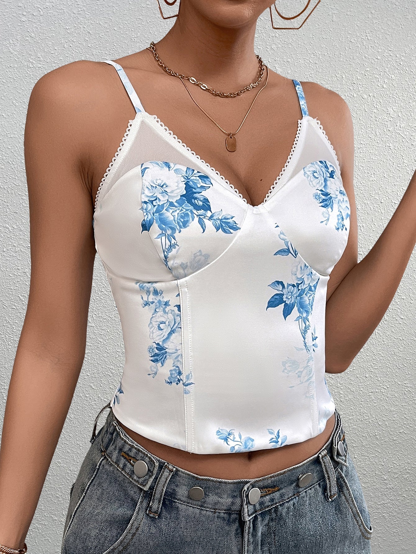 Close-up of the front of a white floral print corset top with blue flowers and sheer mesh detailing.