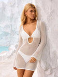 Woman leaning against a white wall wearing a white crochet knit mini dress with a cutout detail.