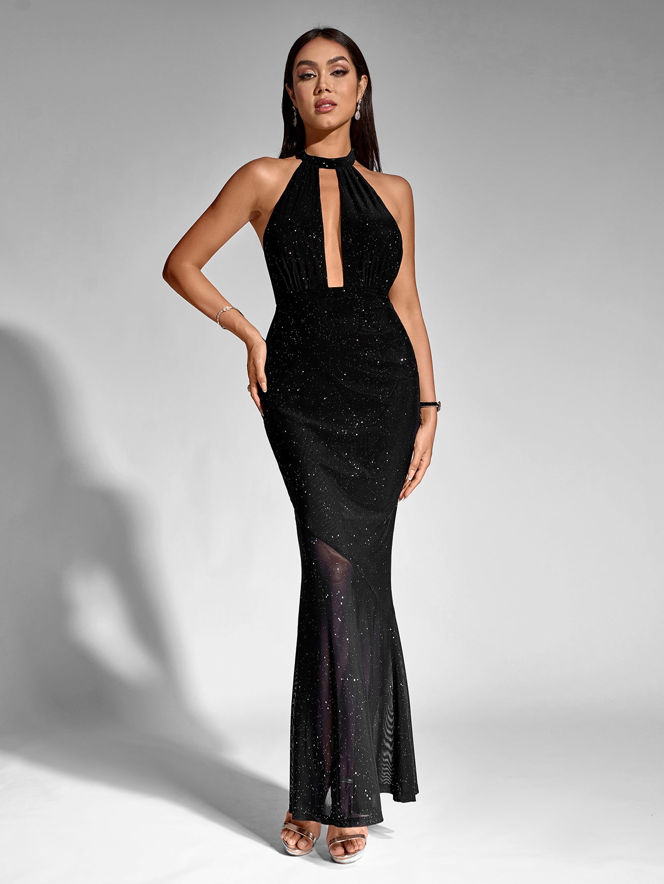 Woman standing with hands on hips in a black sparkling halter neck maxi dress