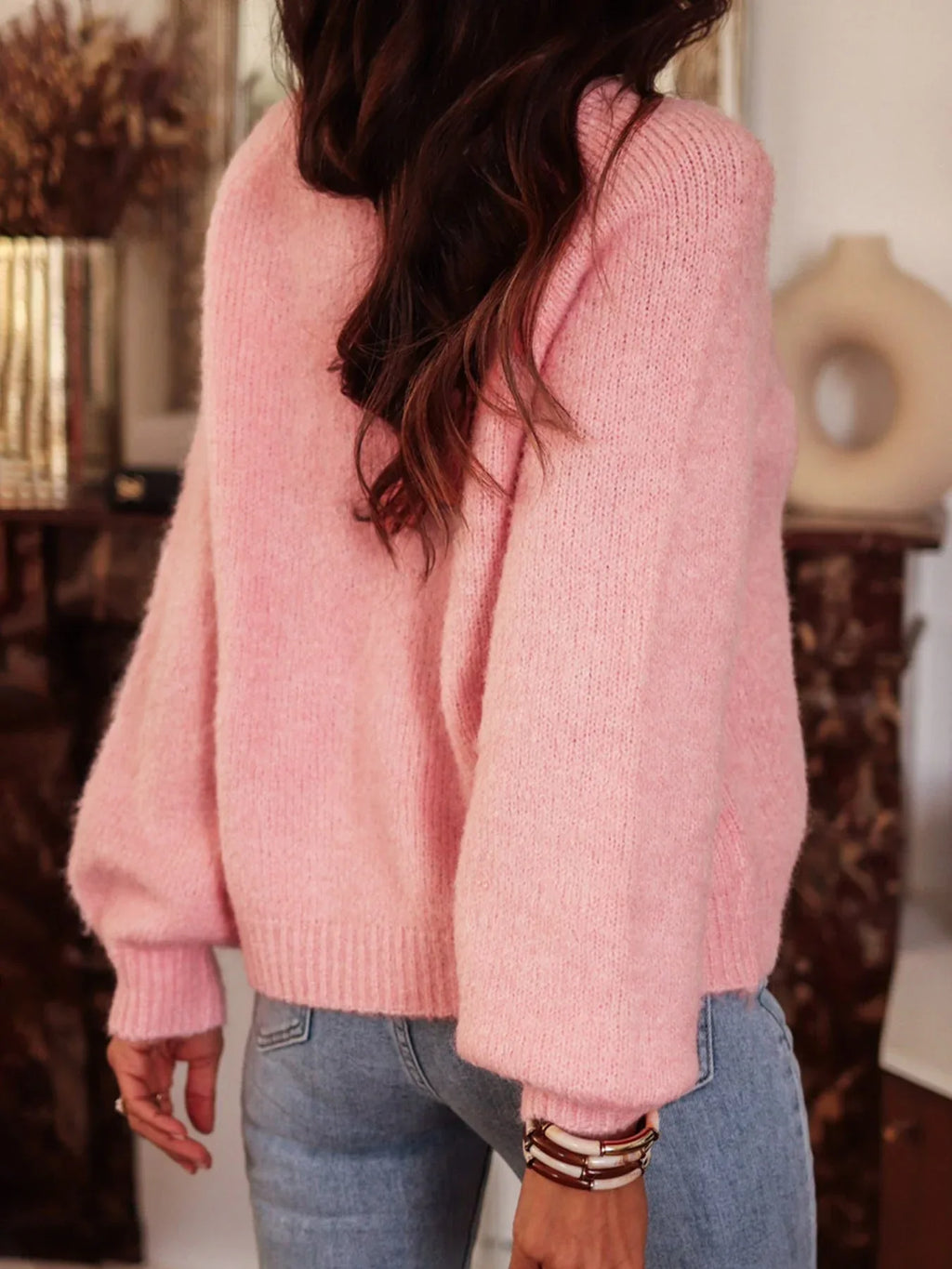 Model showcasing the texture of the pink jeweled button sweater