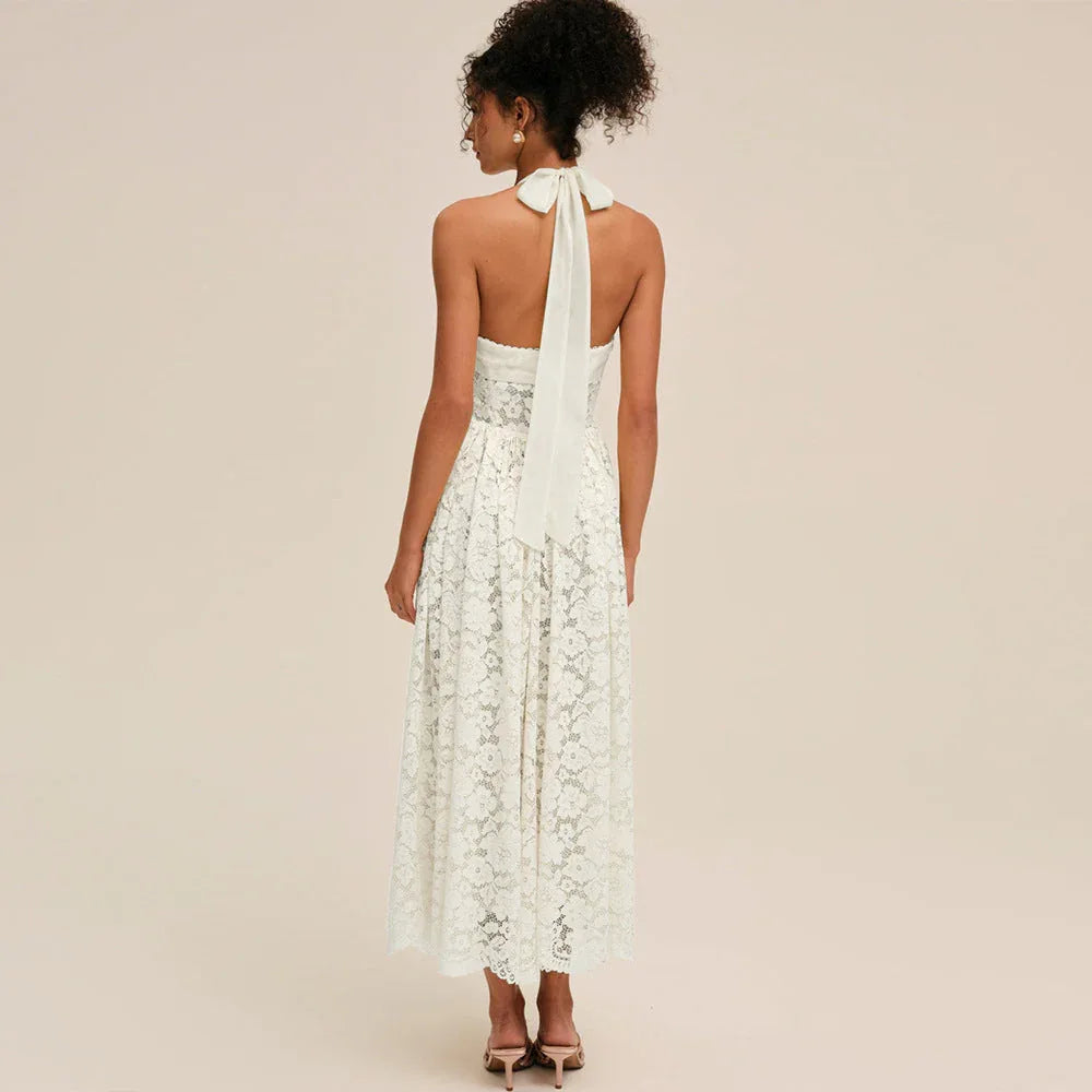 Woman wearing a white lace halter midi dress, back view showing bow detail