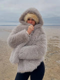 Woman wearing a grey hooded faux fur jacket outdoors