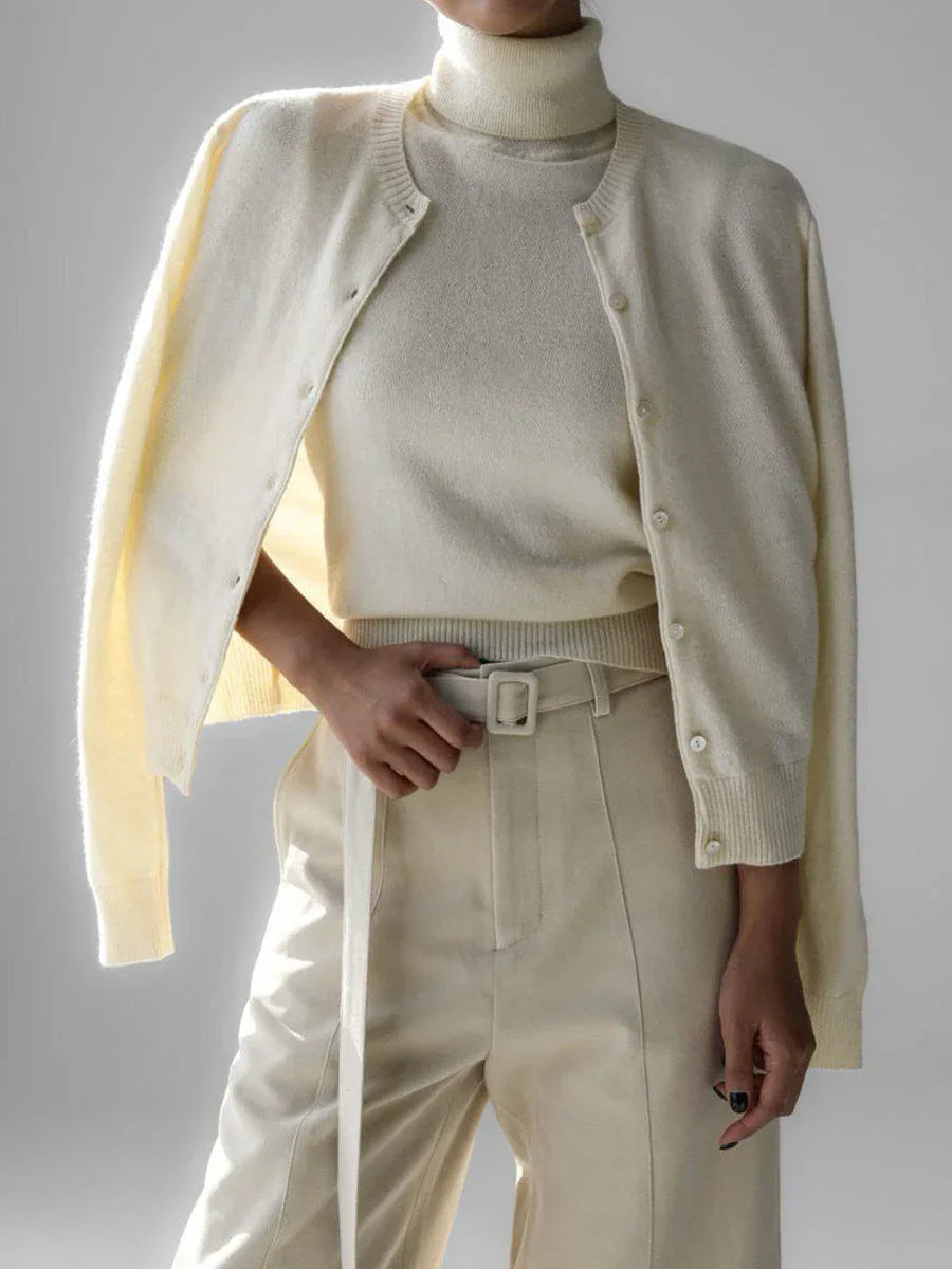 Woman wearing a cream-colored fine knit cardigan over a cream turtleneck and cream trousers