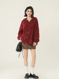 Full body shot of a woman in a red hooded cable knit cardigan and plaid skirt