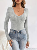 Front view of a woman in a grey ribbed long sleeve V-neck top and distressed jeans.