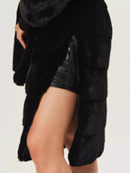 Close-up of the side zipper detail on a black faux fur coat.
