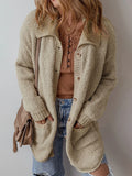Front view of a woman wearing a beige textured knit cardigan over a brown top and blue jeans.