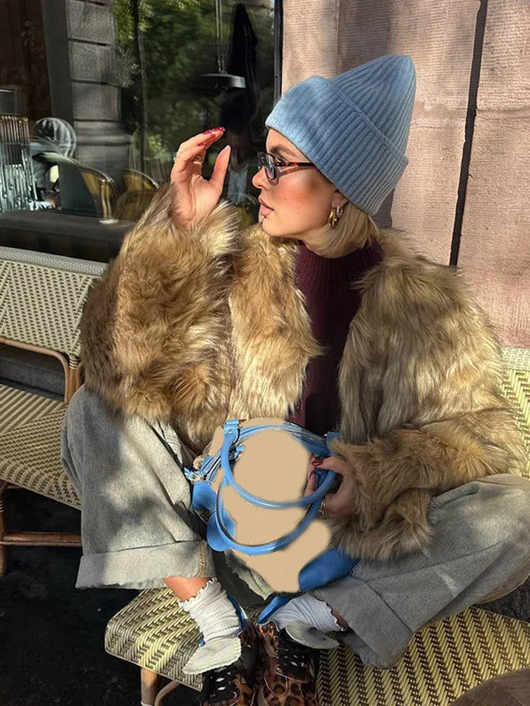 Woman wearing a brown faux fur cropped jacket and a light blue beanie