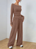 Woman wearing a brown boat neck long sleeve top with ruched waist and wide leg pants