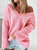 Woman wearing a pink off-the-shoulder v-neck knit sweater with light wash denim shorts.