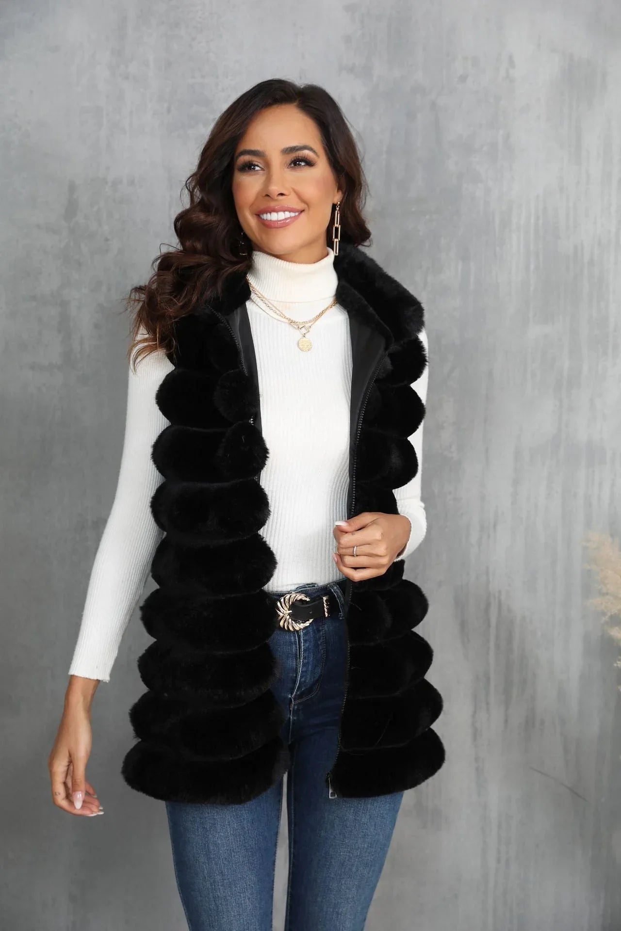 Woman wearing a black faux fur vest with a white turtleneck and blue jeans Main image