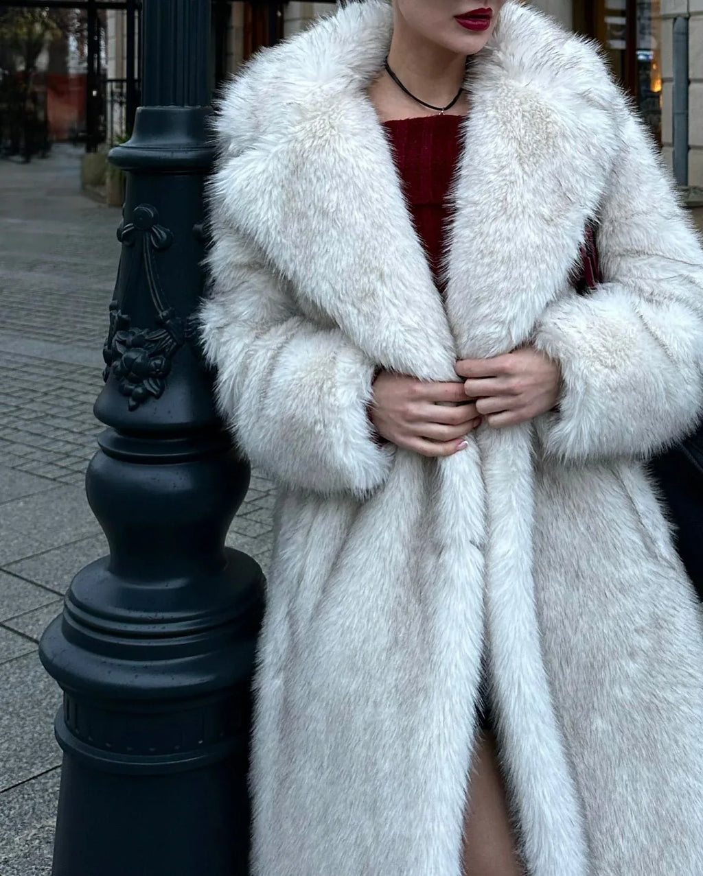 Close-up of a woman wearing a white faux fur coat, showing the lapel and sleeve detail.