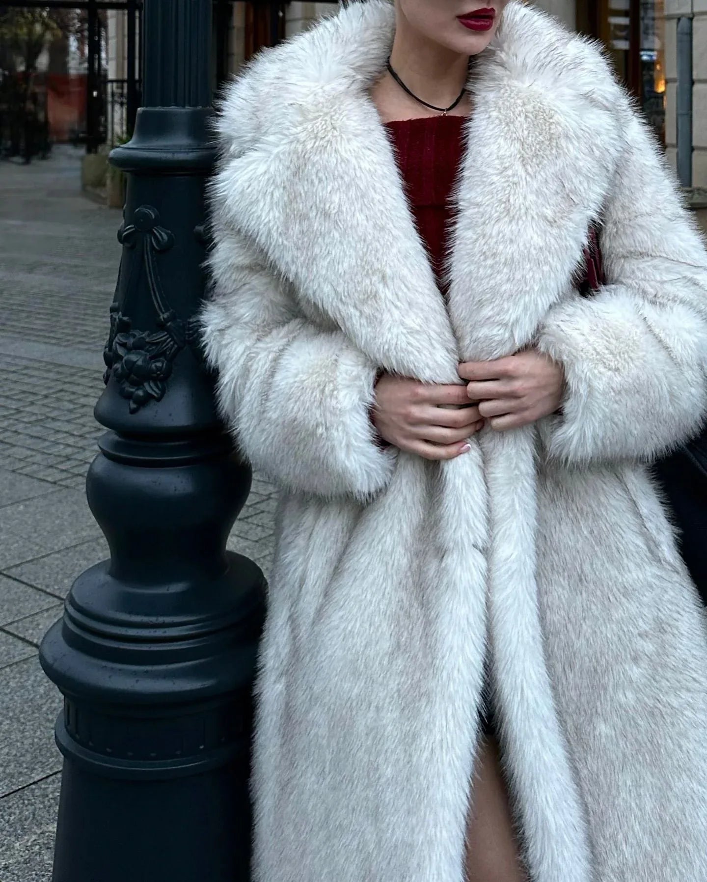 Close-up of a woman wearing a white faux fur coat, showing the lapel and sleeve detail.