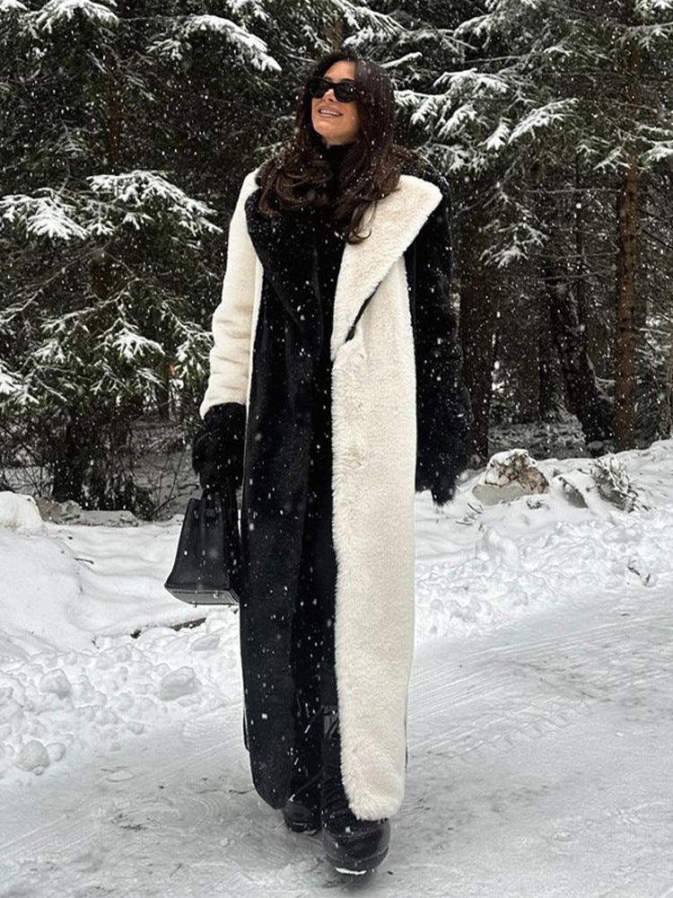 Woman wearing a long black and white color-blocked faux fur coat outdoors in the snow. Main image