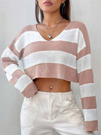 Front view of a woman wearing a pink and white striped cropped knit sweater with a v-neckline, styled with white pants.