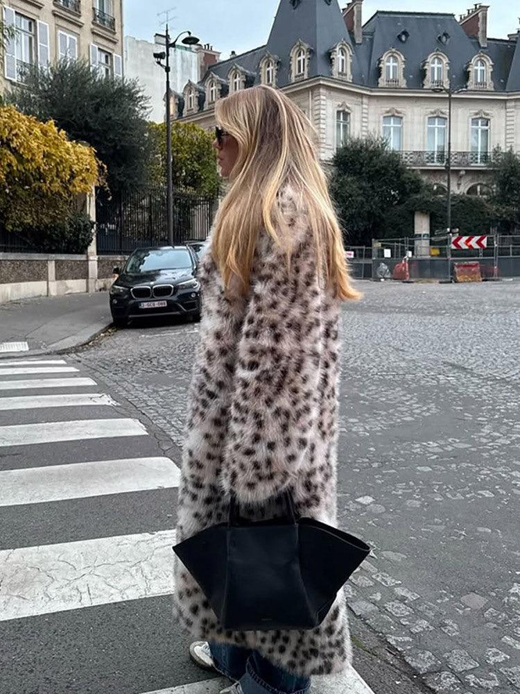 Woman wearing a long leopard print faux fur coat with a black tote bag in a city.