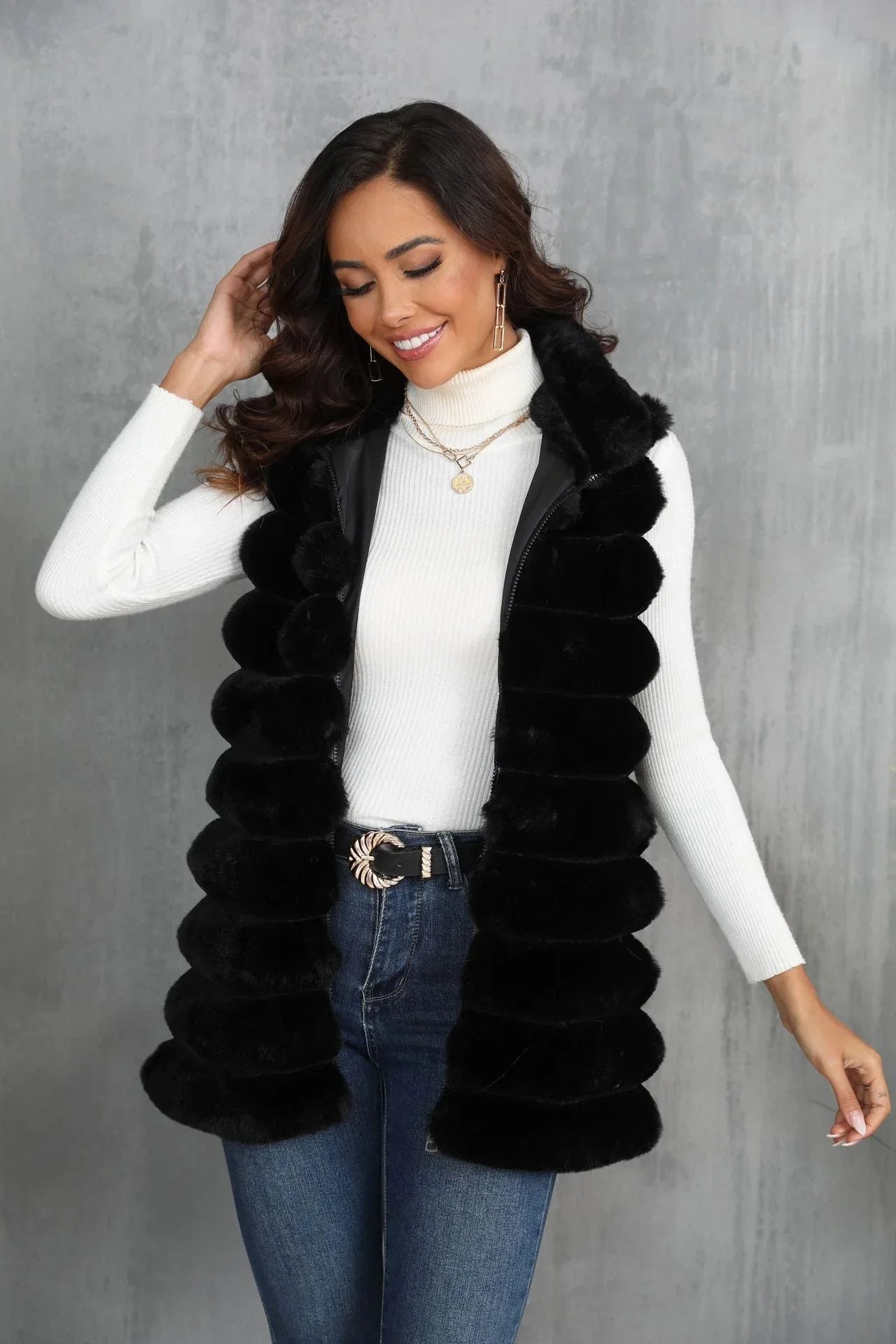 Woman smiling and touching her hair while wearing a black faux fur vest