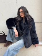 Woman sitting down wearing a black faux fur jacket and wide-leg jeans.