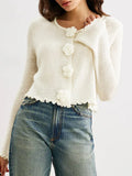 Model showing the front of a white knit cardigan with a round neckline and bell sleeves.