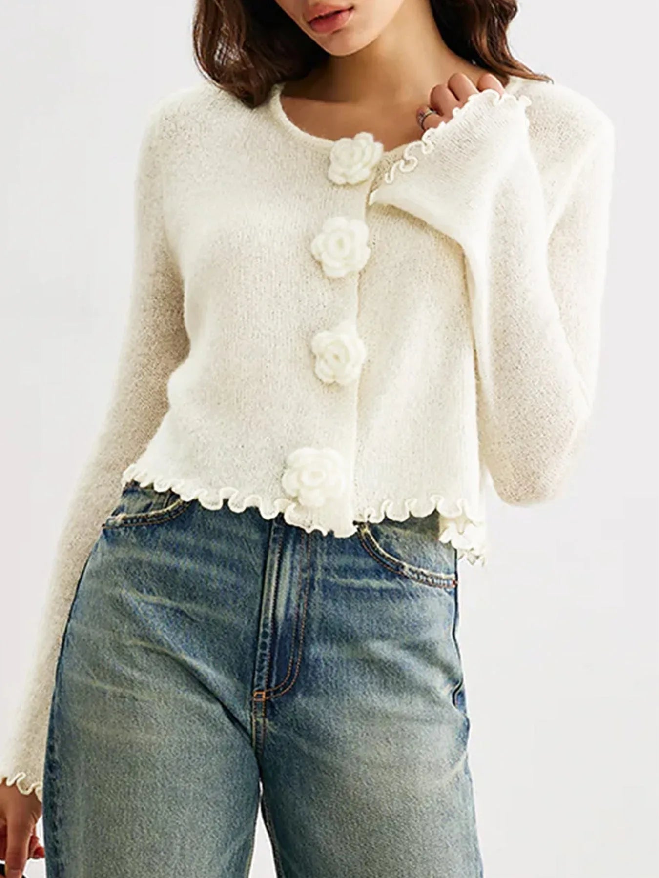 Model showing the front of a white knit cardigan with a round neckline and bell sleeves.
