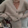 Close-up of the textured knit fabric of a beige cardigan and skirt set