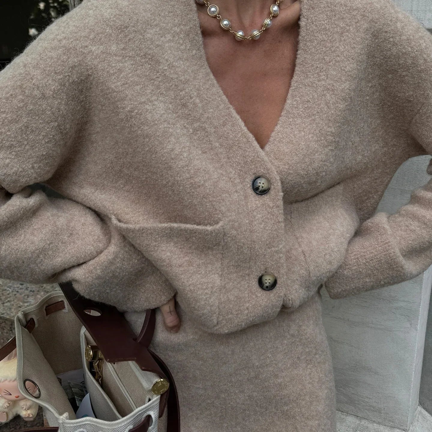 Close-up of the textured knit fabric of a beige cardigan and skirt set