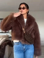 Woman wearing a brown faux fur jacket and blue jeans posing for a photo