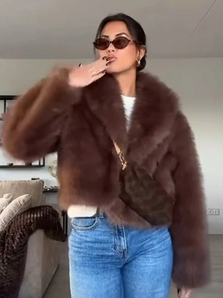 Woman wearing a brown faux fur jacket and blue jeans posing for a photo