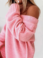 Woman posing in a pink off-the-shoulder knit sweater, showing the sleeve detail.