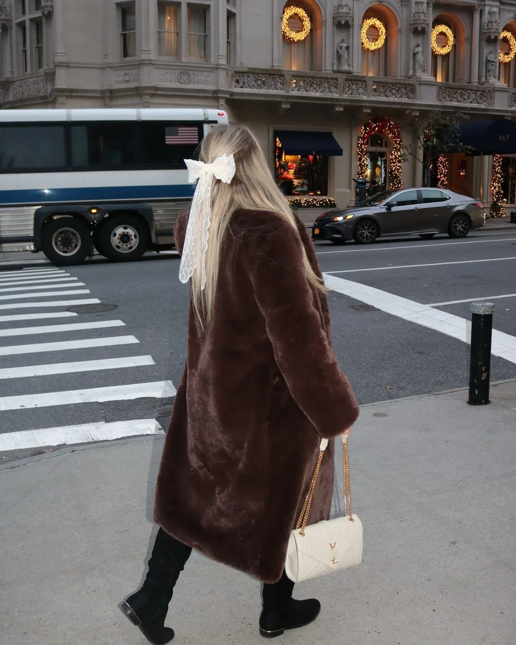 Woman walking on a street wearing a long brown faux fur coat
