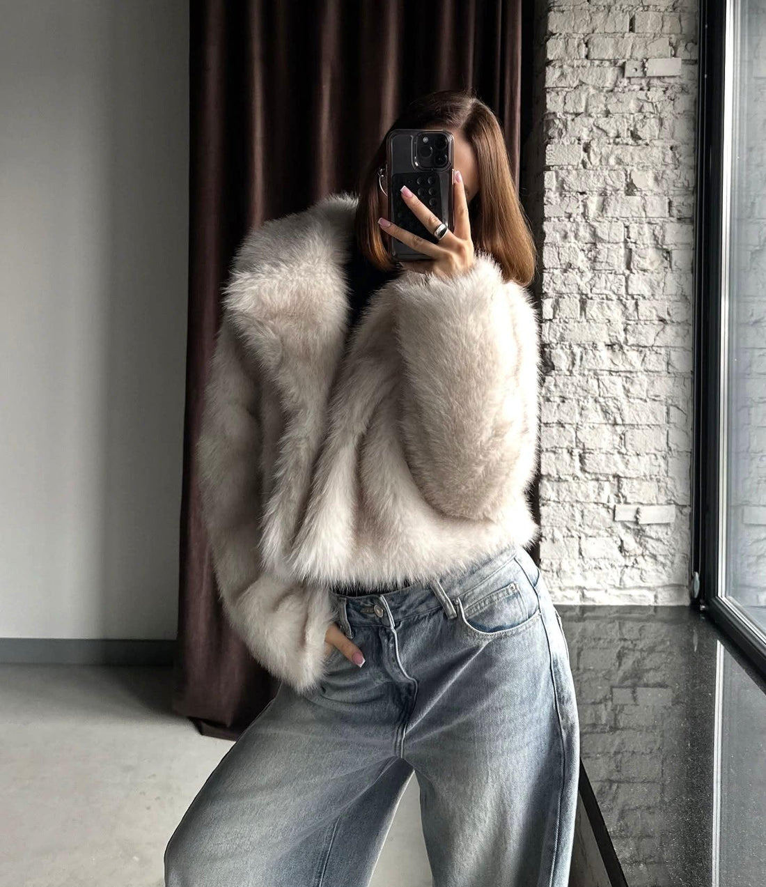 Woman wearing a cream-colored faux fur cropped jacket with a notch lapel collar and long sleeves.