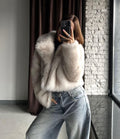 Front view of a woman in a cream faux fur jacket and light wash wide-leg jeans.
