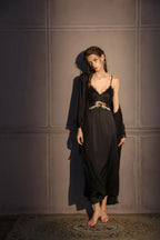 Full body shot of a woman in a black satin slip dress with lace bust detail and a matching black robe.