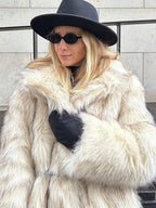 Close-up of a woman in a cream-colored faux fur coat, black gloves, and black hat.
