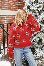 Woman posing in a red holiday sweater with a reindeer pattern