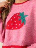 Detailed view of the strawberry graphic on a pink knit sweater.
