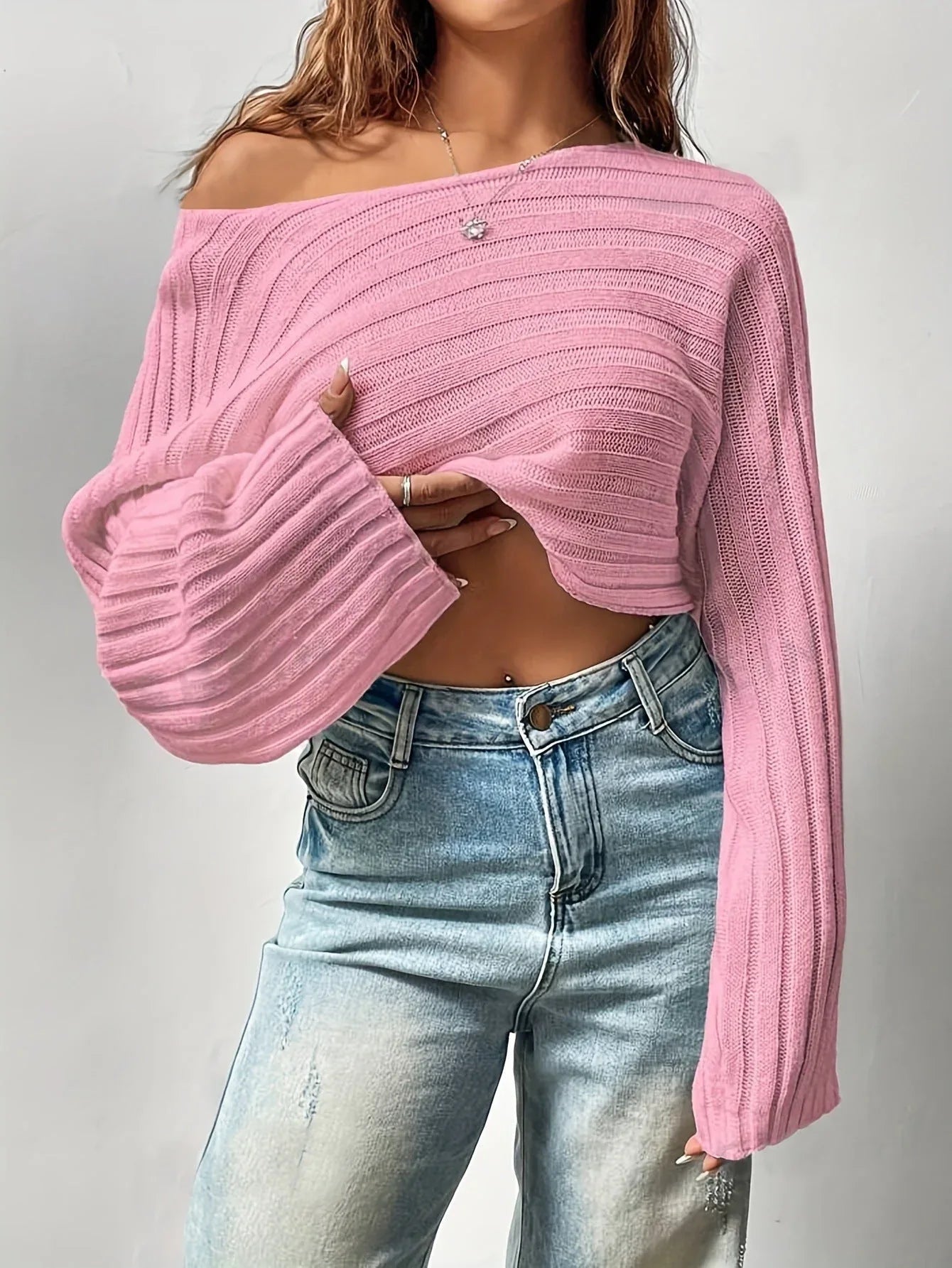 Model showing the off-the-shoulder styling of a white cropped sweater