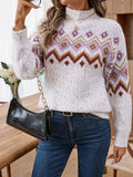Woman holding a black handbag with a gold chain strap, wearing a white knit sweater with a geometric pattern.