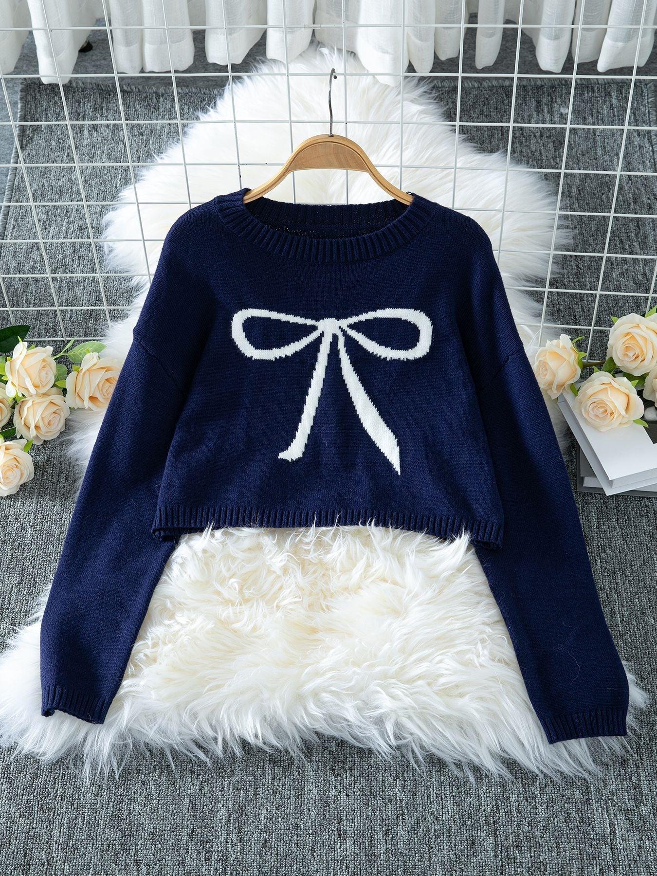 Navy blue cropped sweater with a white bow graphic, displayed on a hanger.